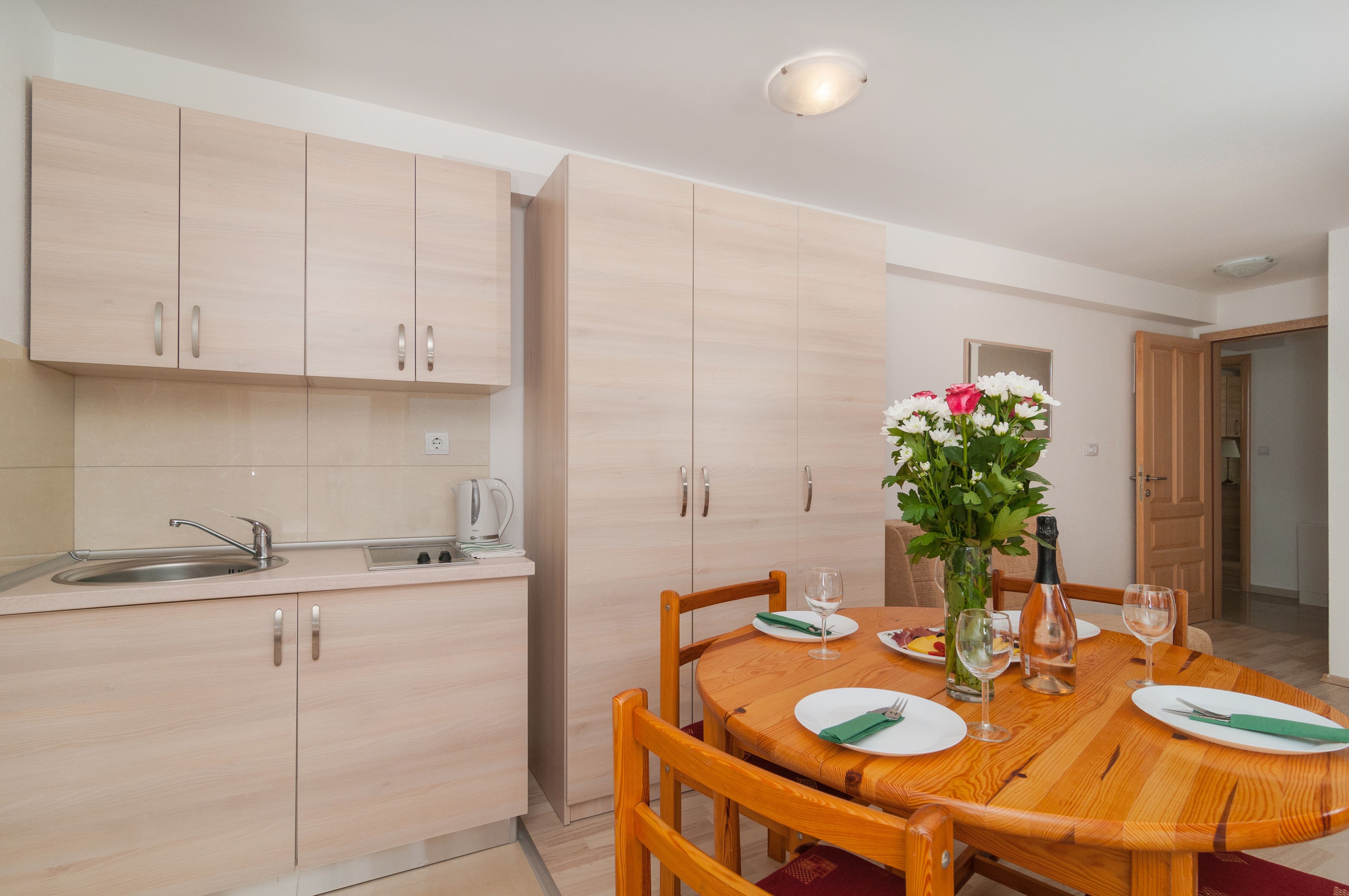 A modern kitchen with wooden cabinets and a dining table set for four.