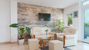A modern living room with a stone wall, a flat-screen TV, and comfortable seating. - Villa Juraj (Bol)