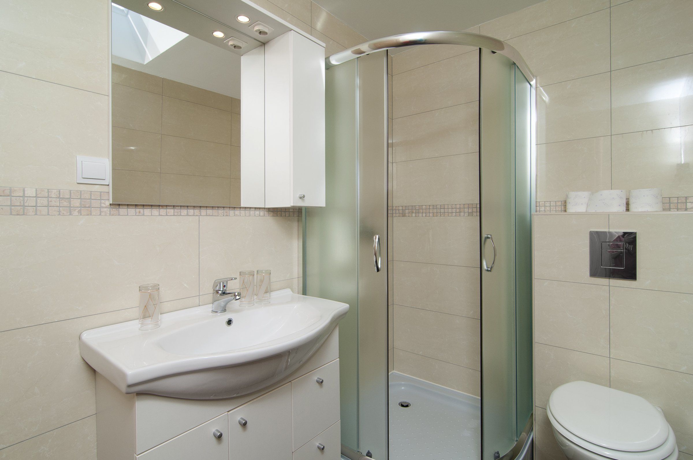 Un baño moderno con una cabina de ducha curva, un lavabo blanco y un inodoro.