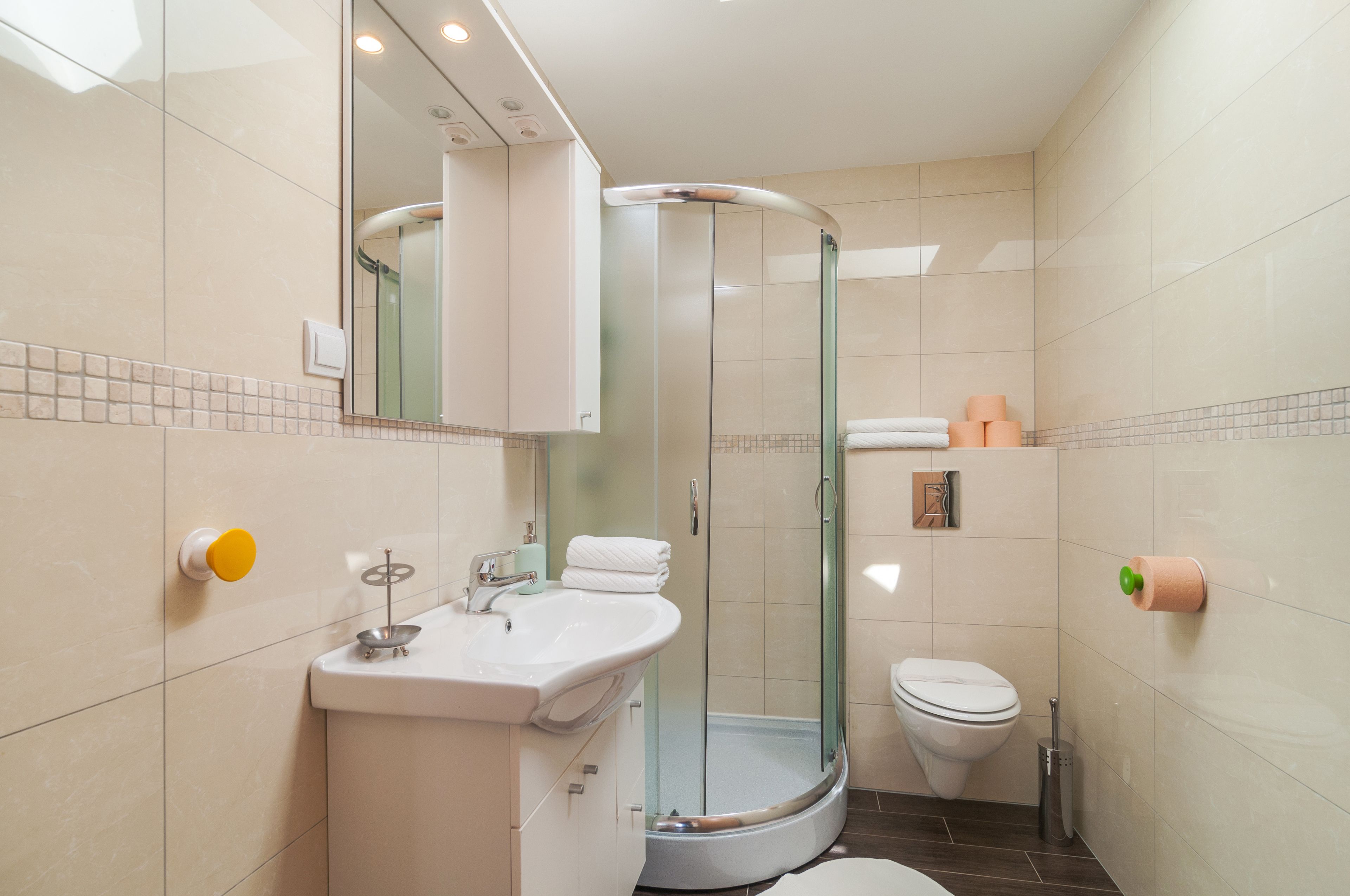 A modern bathroom with a glass-enclosed shower, a white sink, and a toilet.