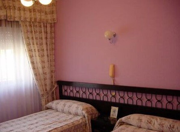A room with two beds, a pink wall, and a window with curtains. - Hostal Restaurante Torremar (Medinaceli)