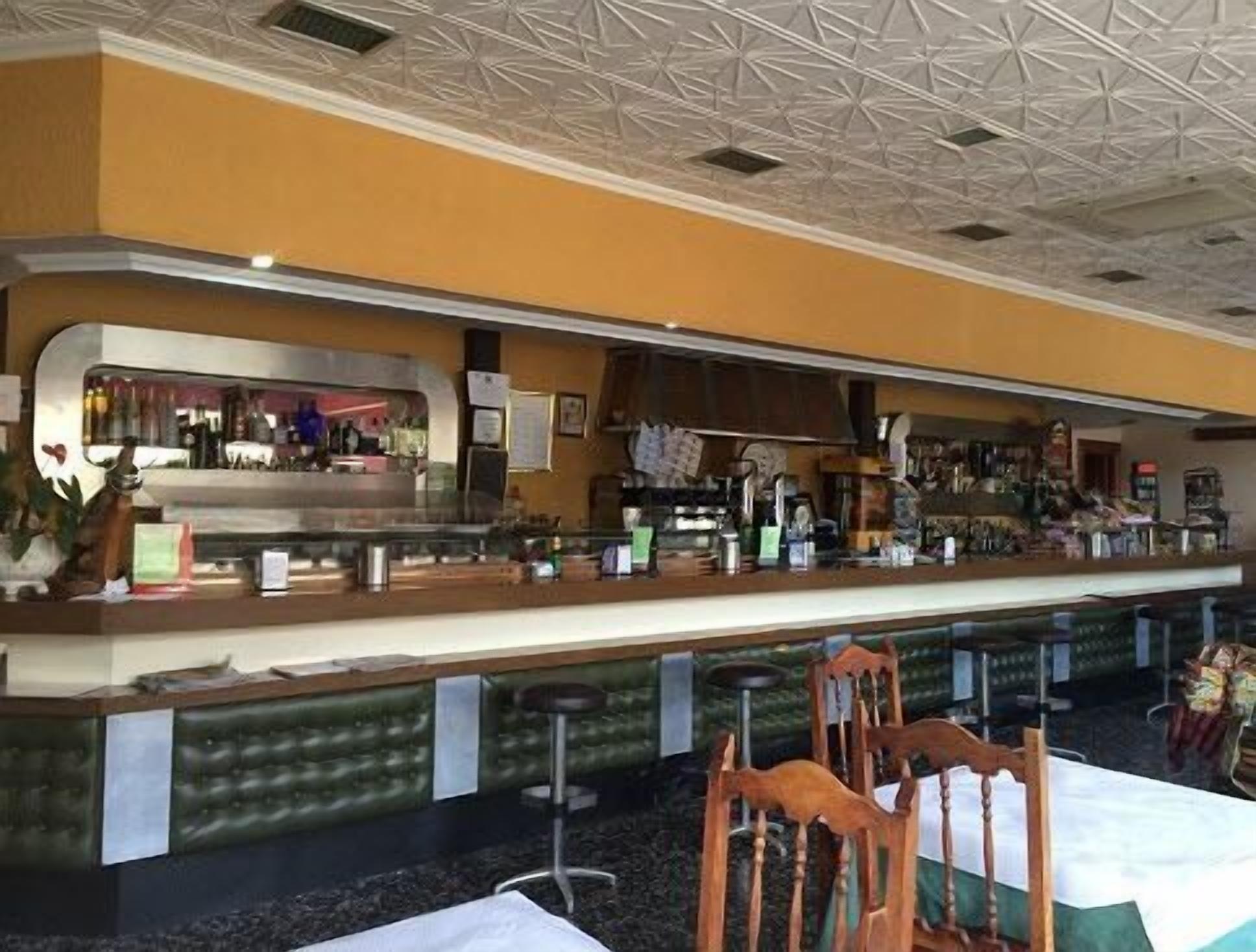 Eine Bar mit Theke, Barhocker und einer Sitzecke mit Stühlen.
