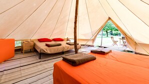 Een tent met een bed, een tafeltje en een stoel.