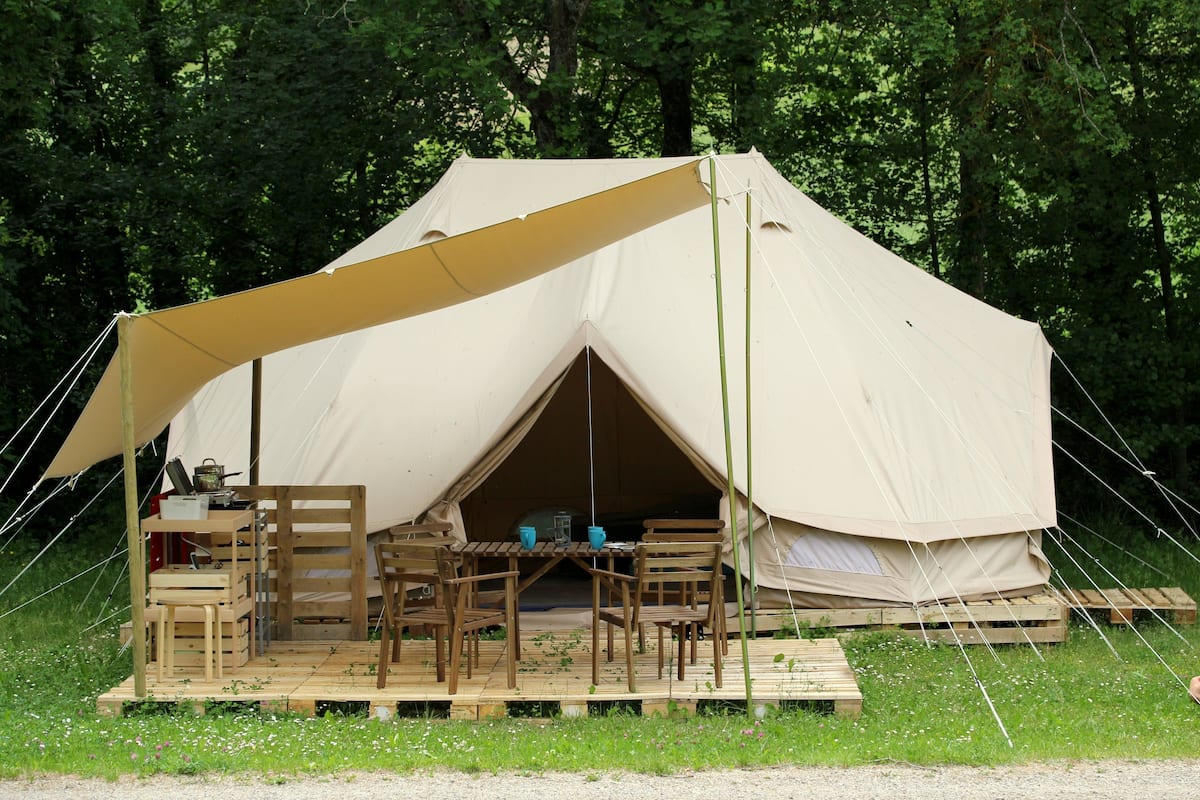 Una carpa con una terraza de madera, mesas y sillas dispuestas para comer.