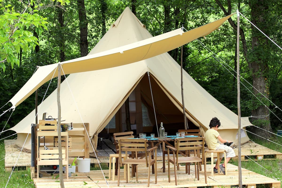 Una carpa con una mesa y sillas instaladas en un bosque.