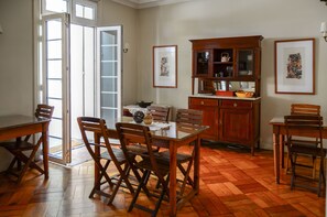 A dining area with wooden furniture, a glass table, and a wooden cabinet with glass doors. - Vilafranca Petit Hotel (Santiago)