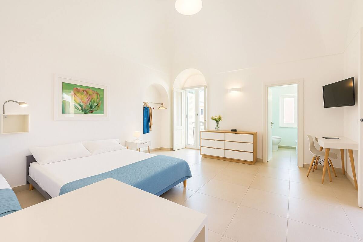 Una habitación de hotel moderna con una cama grande, un escritorio y una televisión.