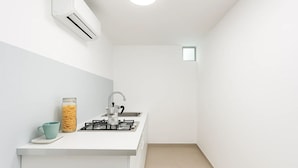 Une petite cuisine équipée d’une cuisinière à gaz, d’un évier et d’un bocal de pâtes.
