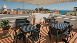 A terrace with outdoor furniture, a view of a coastal cityscape, and a dome building in the background. - Gioia 13 Apartments & Rooms (Procida)