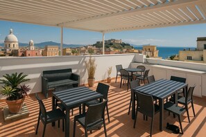 A terrace with outdoor furniture, a view of a coastal cityscape, and a dome building in the background. - Gioia 13 Apartments & Rooms (Procida)