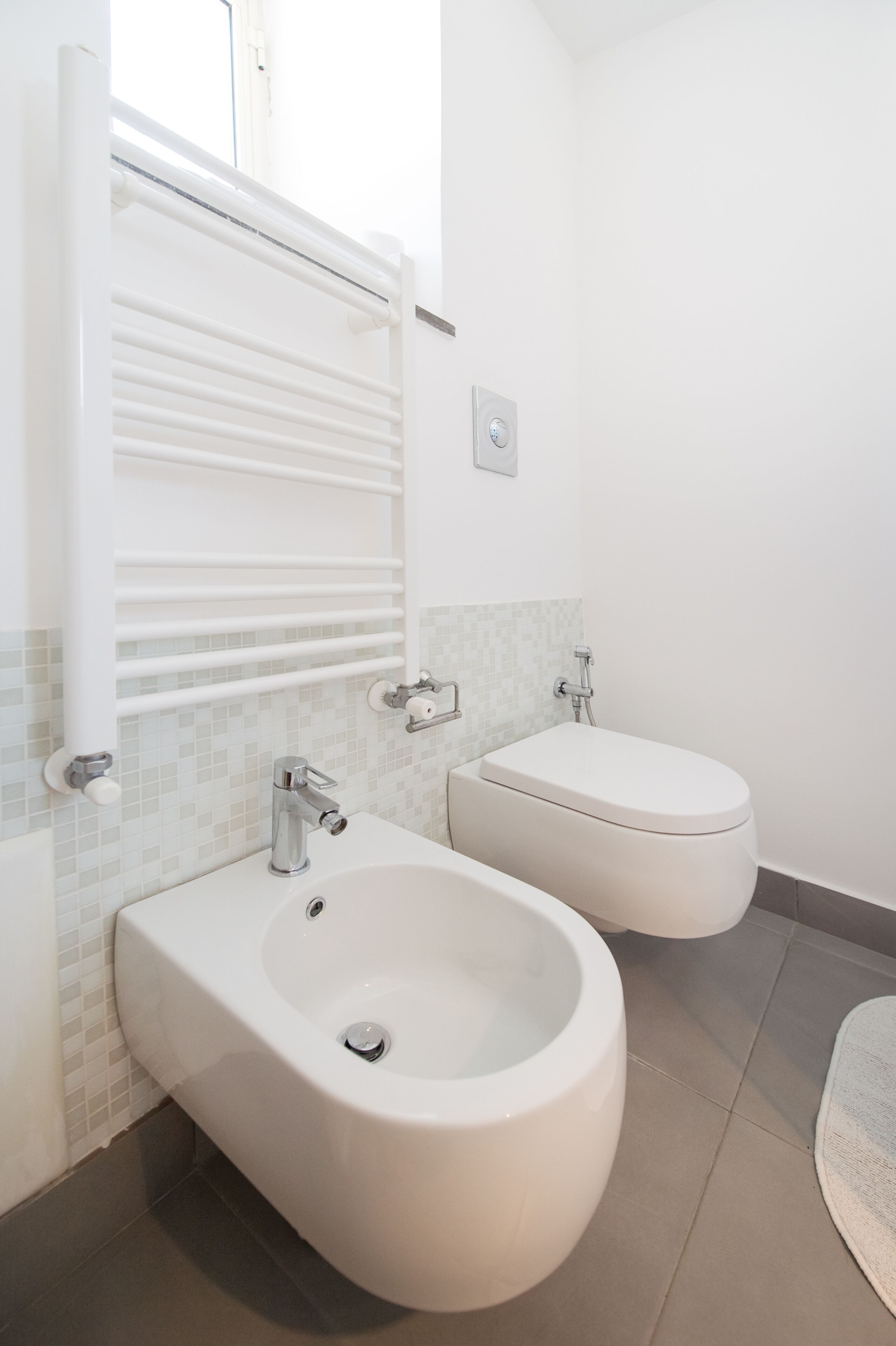 Et moderne badeværelse med toilet, vask og spejl.