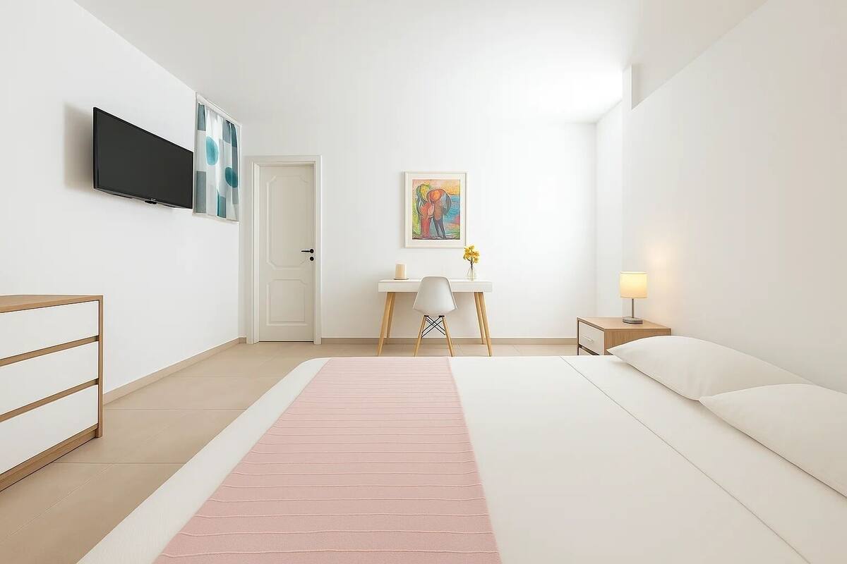 Una habitación de hotel moderna con una cama, un escritorio, una silla, un televisor y un cuadro en la pared.