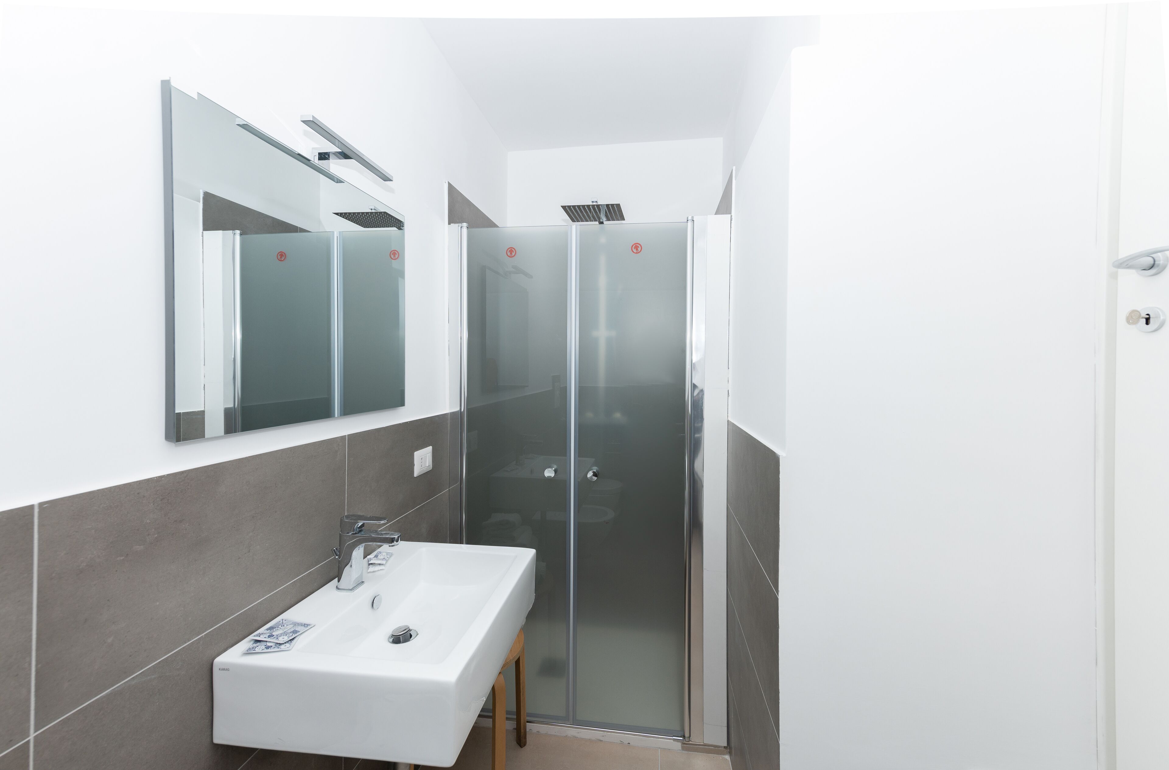 A modern bathroom with a glass-enclosed shower, a white sink, and a mirror above it.