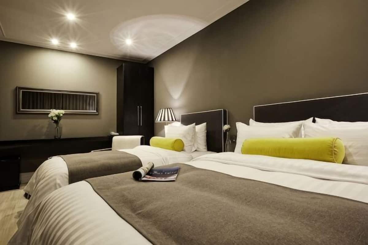 Une chambre d’hôtel moderne avec deux lits, une table de chevet, une lampe et une œuvre d’art accrochée au mur.