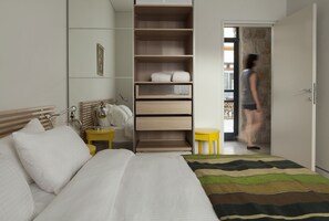 A hotel room with a bed, a bedside table, a wardrobe, and a small table with a lamp. - Pnai - Villa in the Galilee (Rosh Pinna)