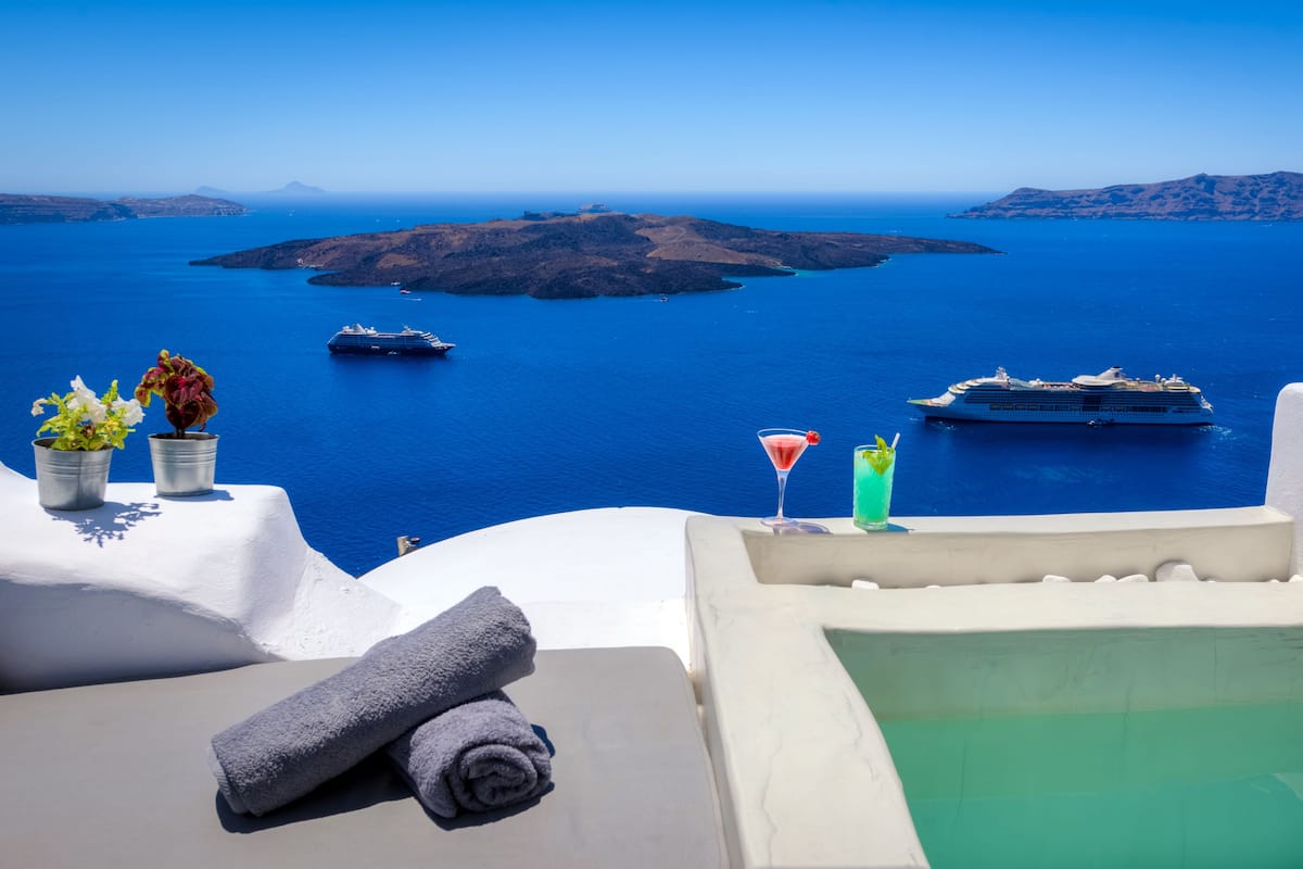 Vista al mar con piscina infinita blanca, un pequeño bar con bebidas, y vistas al mar y a las islas.