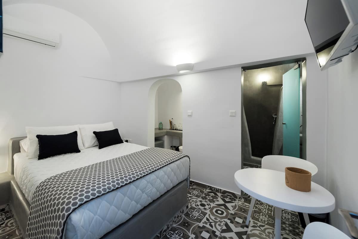Una habitación de hotel con cama, una mesita y zona de ducha.
