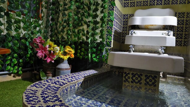 A bathroom with a tiled sink, a small fountain, and a wall covered in green foliage. - Azcami Boutique Hotel (Puebla)