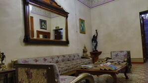 A living room with a floral sofa, a wooden coffee table, and a large mirror. - Azcami Boutique Hotel (Puebla)