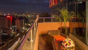 A balcony with wicker furniture, a potted plant, and a floral arrangement.