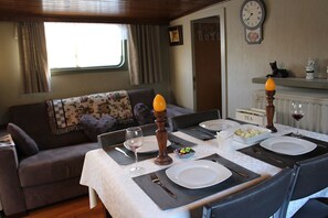 Et spiseområde med et bord dækket til to personer, en sofa, et ur og en radiator med teksten 