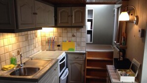 A compact kitchen with white cabinets, a sink, a stove, and a small countertop. - Spits-Lucie B&B (Izegem)