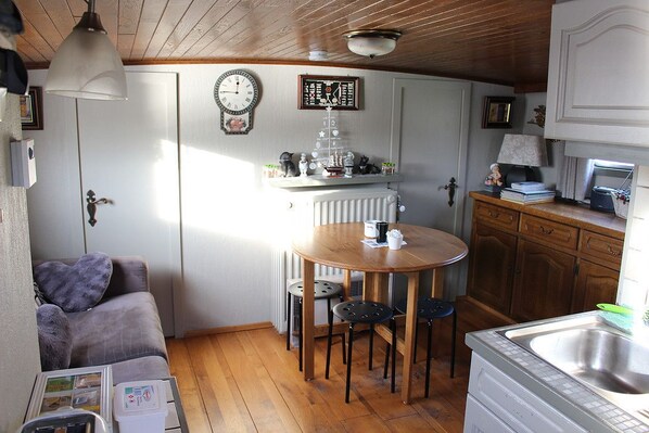 A cozy kitchen with a wooden table, chairs, a radiator, and a clock on the wall.