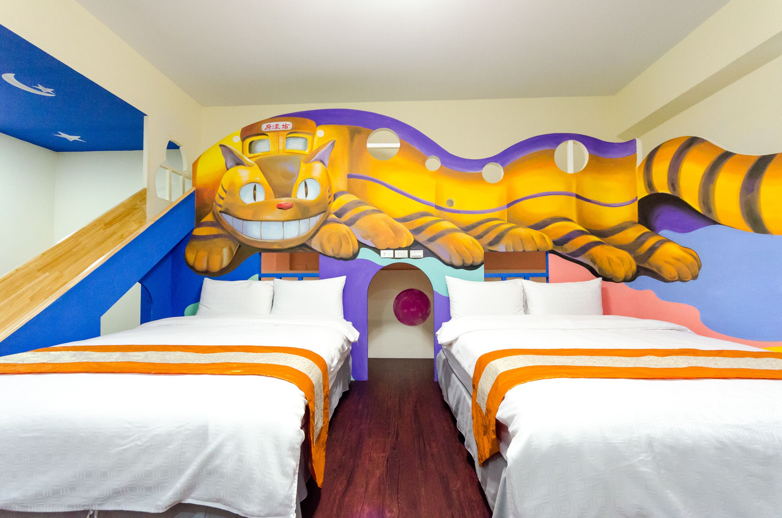 A hotel room with two beds, a large mural of a tiger, and a slide.