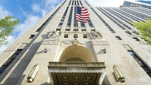 The LeVeque Tower hotel entrance with an American flag, stone facade, and a classic architectural design. - Hotel LeVeque, Autograph Collection (Columbus)