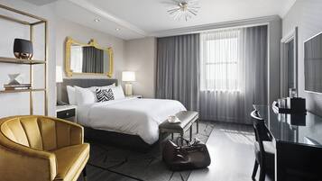Una habitación de hotel moderna con una cama grande, un escritorio, una silla y un espejo.
