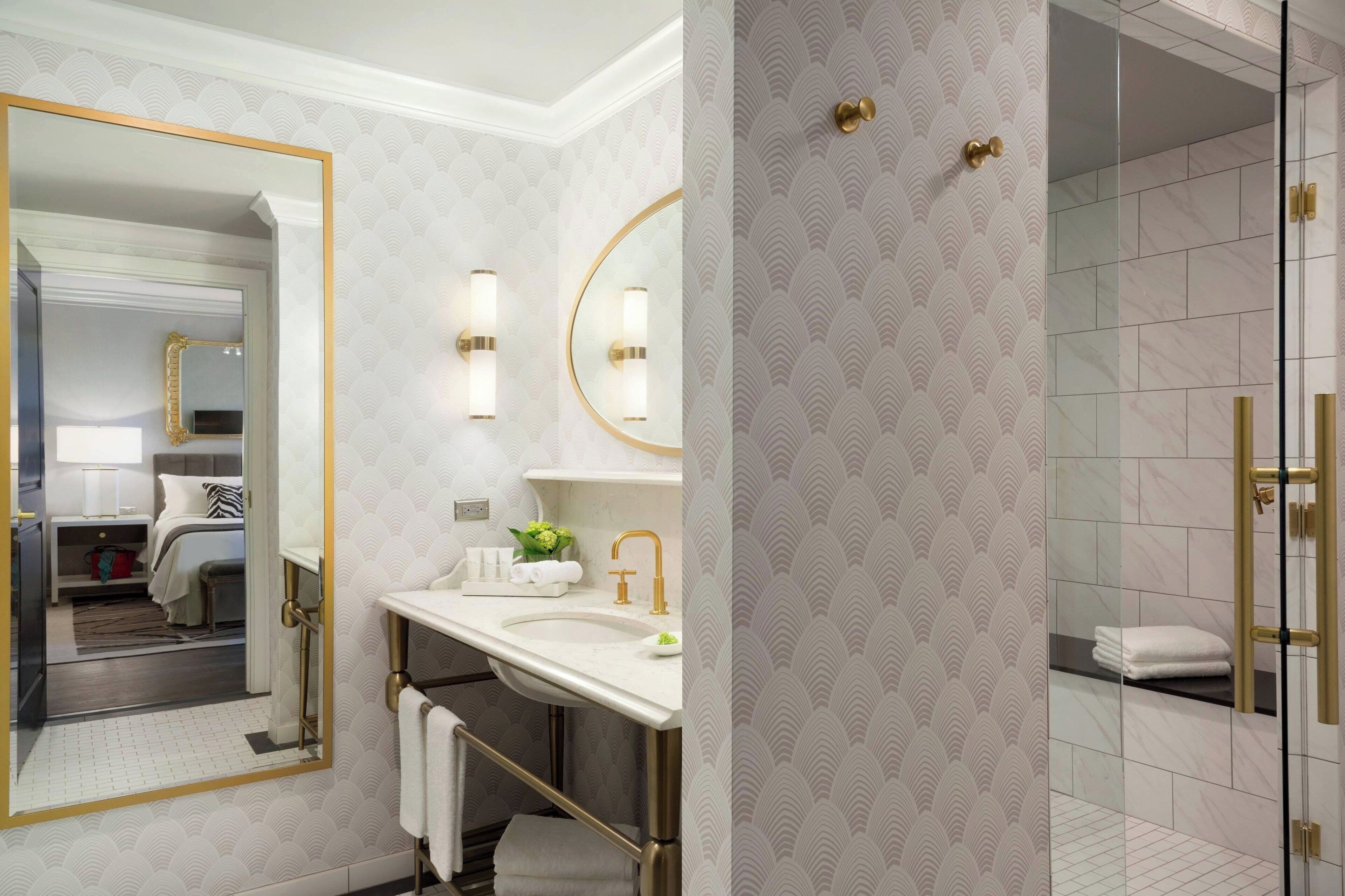 A modern bathroom with a large mirror, a sink, and a shower area.