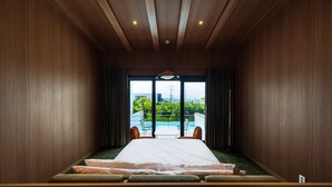 A modern hotel room with a large bed, a view of a swimming pool, and a balcony. - VILLASAGYE (Seogwipo)