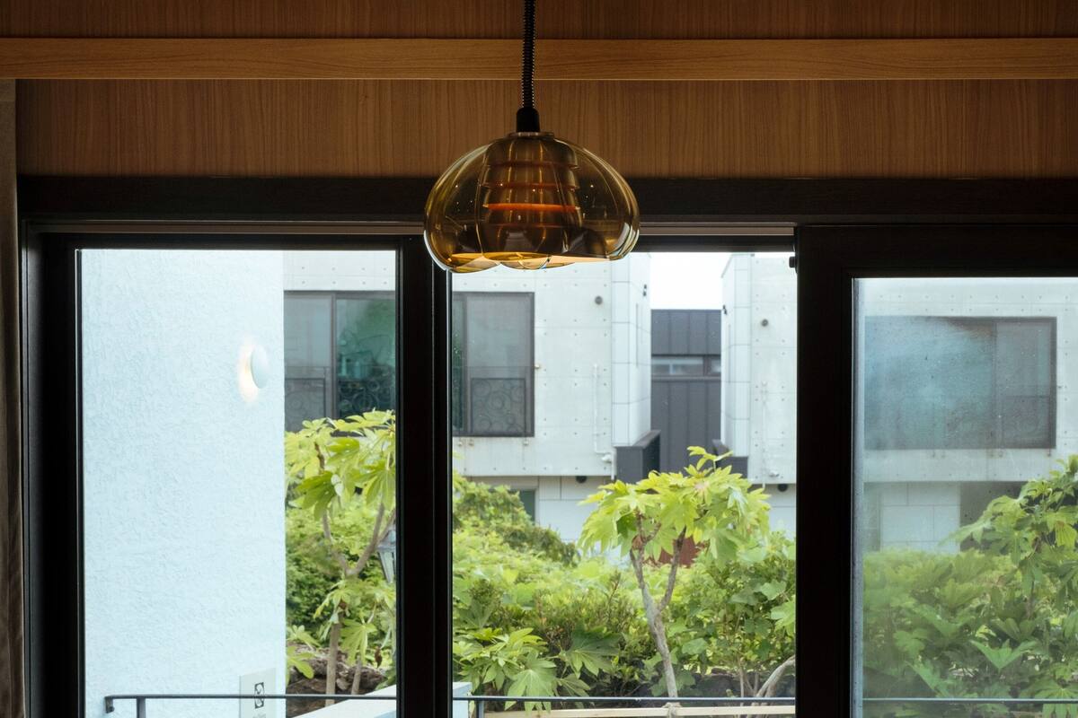 A hotel room with a bed, a table, and two chairs. There is a view of a swimming pool and greenery outside.