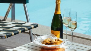 A table with a bottle of champagne, two glasses, a plate of food, and a bucket, set against a poolside view. - VILLASAGYE (Seogwipo)