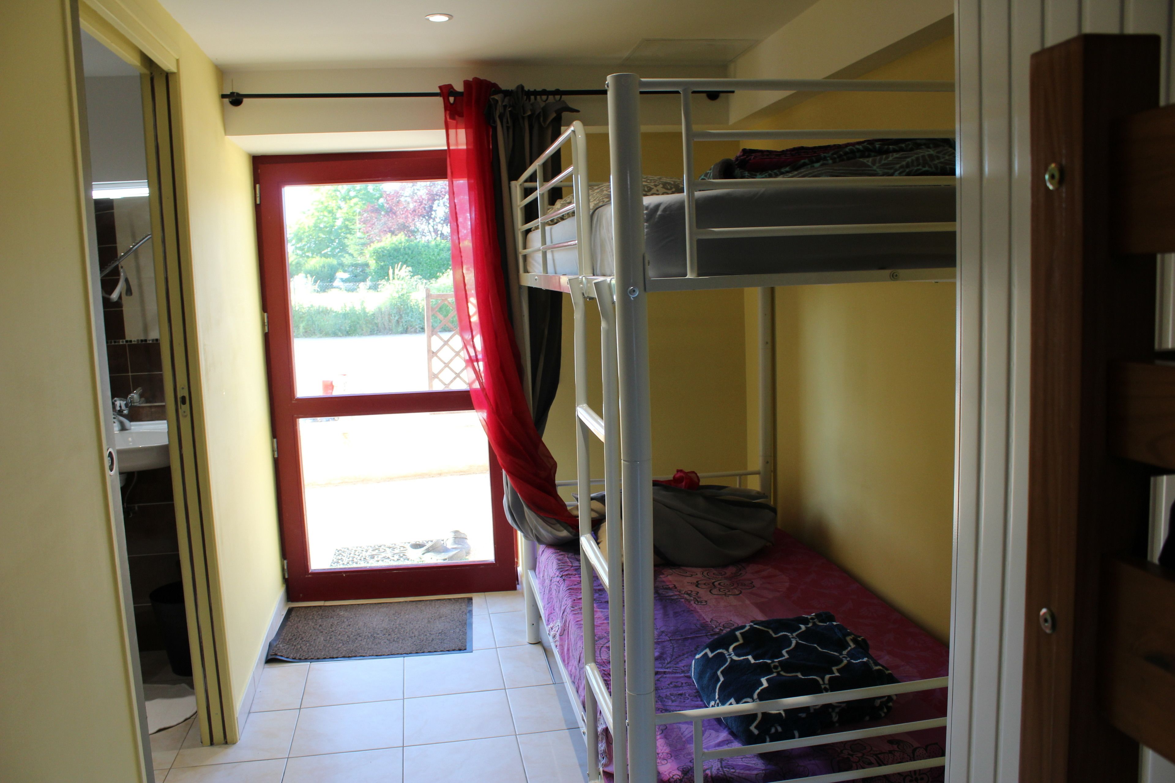 A bunk bed room with a door leading to a balcony.