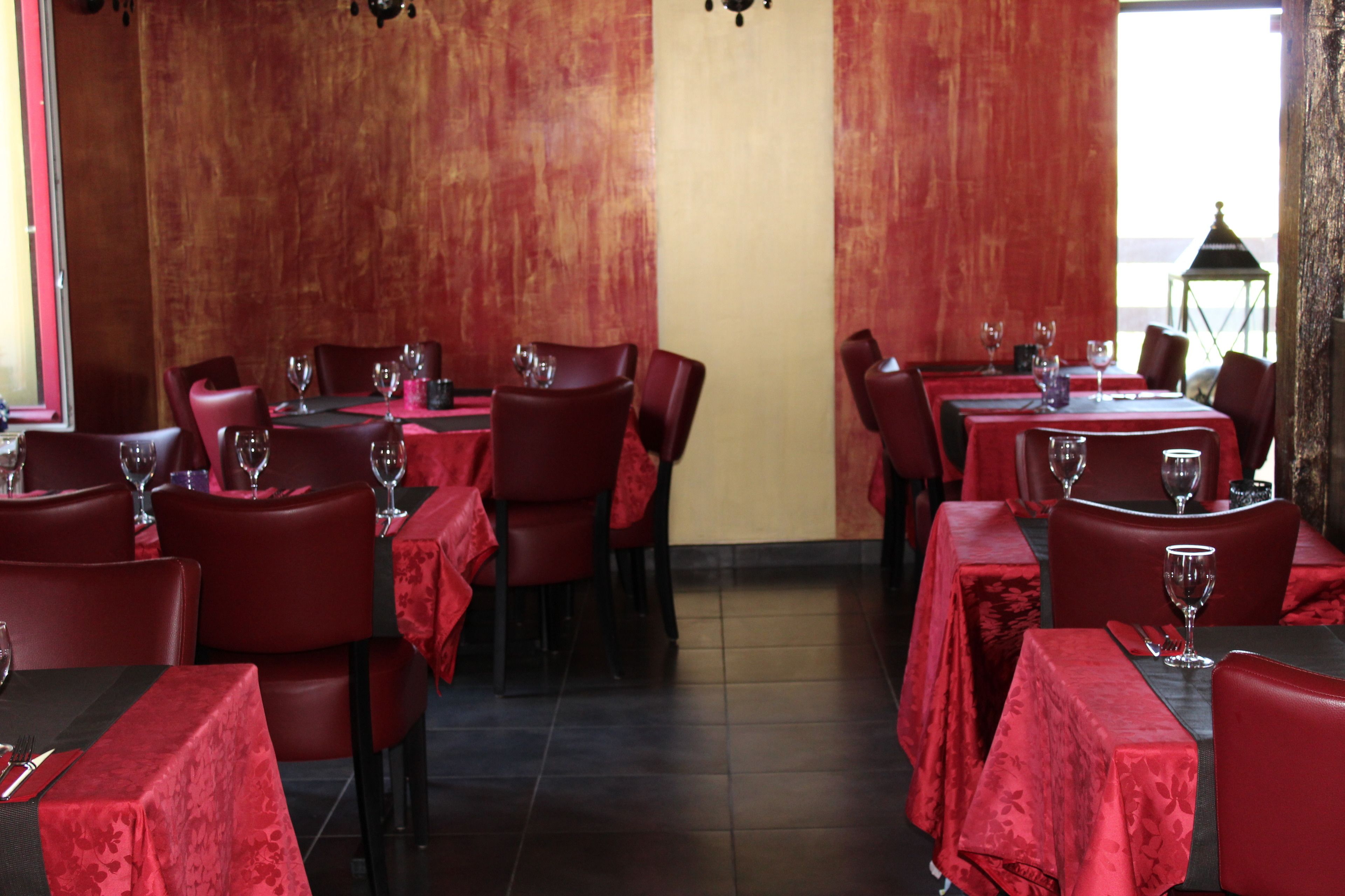 Un restaurant avec des nappes rouges, des chaises rouges et une vue sur la mer.