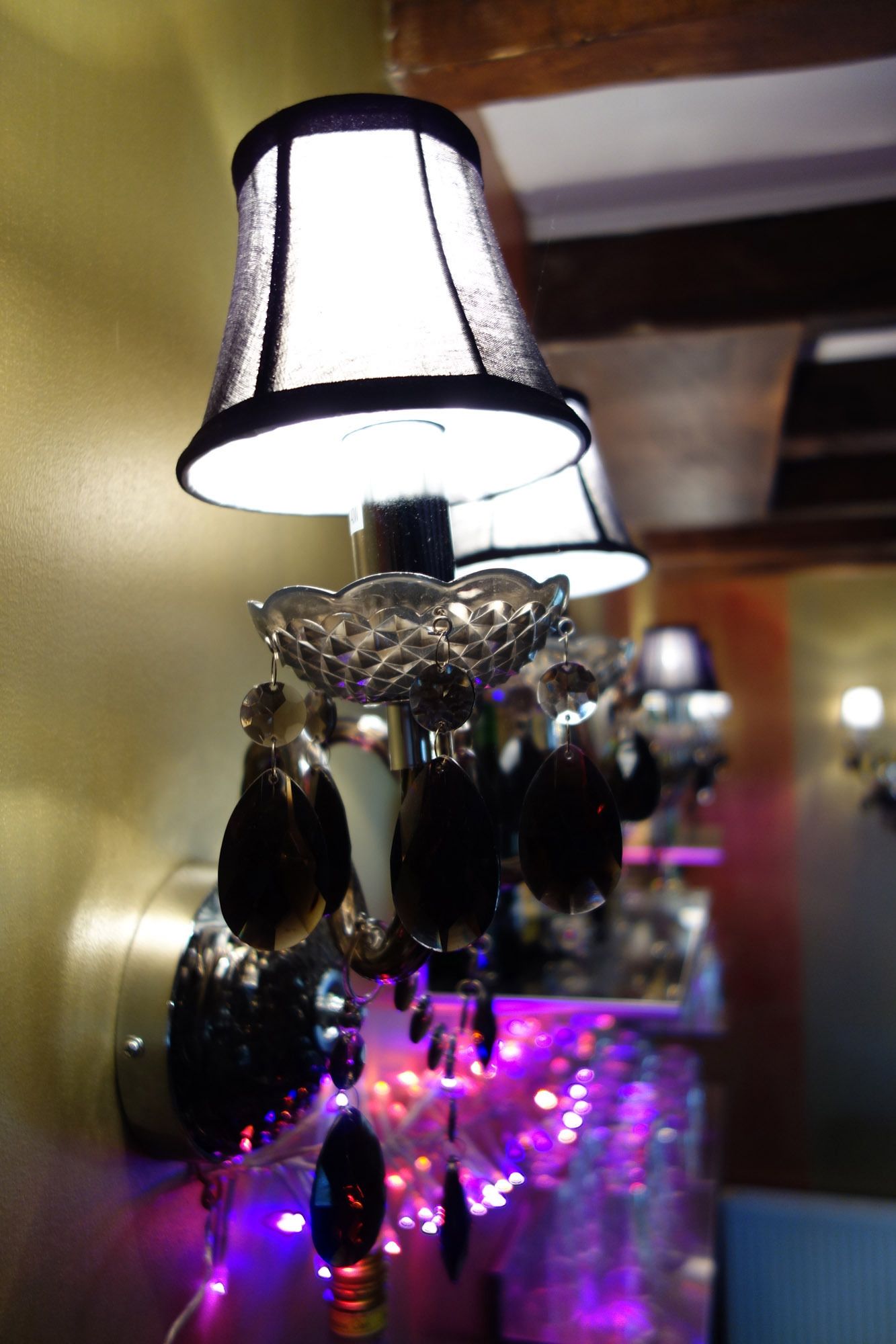 A wall-mounted lamp with a black shade and decorative elements.