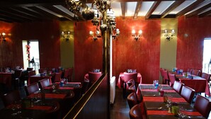 Un restaurant aux murs rouges, doté de nombreuses tables et d’une allée centrale.