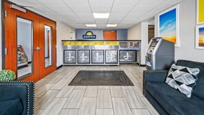 A hotel lobby with a reception desk, Days Inn sign, ATMs, and a black leather couch. - Days Inn by Wyndham New Orleans Pontchartrain (New Orleans)