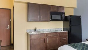 A compact hotel room with a kitchenette including a microwave, refrigerator, and wooden cabinets. - Days Inn by Wyndham New Orleans Pontchartrain (New Orleans)