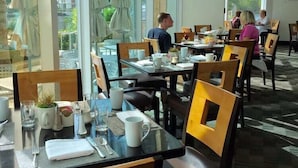 A restaurant with large windows, tables set with white tableware, and outdoor umbrellas. - Gallery One Private Condos (Fort Lauderdale)