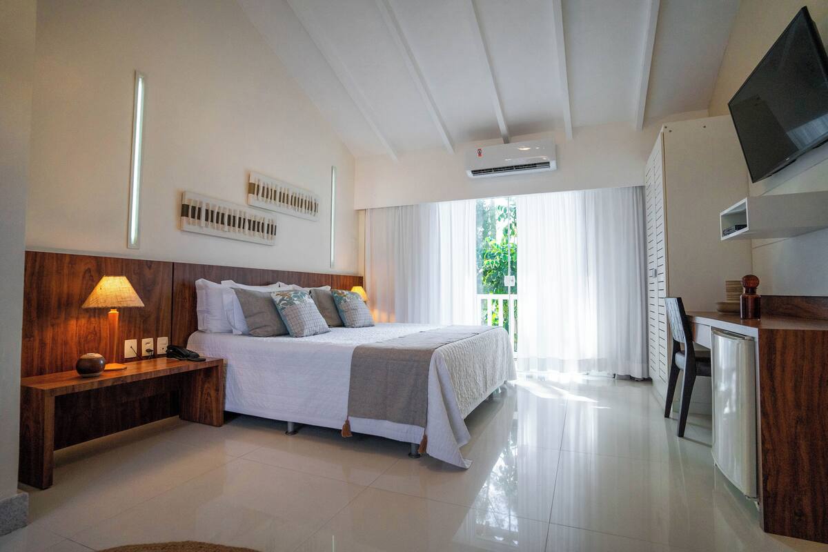 Une chambre d’hôtel moderne avec un grand lit, une table de chevet, une lampe et un téléviseur fixé au mur.