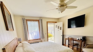 Un dormitorio con una cama, un escritorio, una silla, un teléfono y un televisor en la pared.