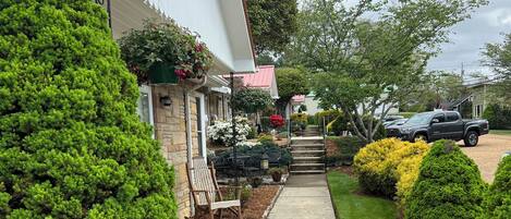 A residential driveway leading to a house with a stone foundation and a red roof.