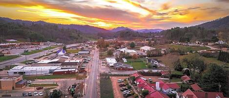 A town with a central road, buildings, and a mountainous backdrop.