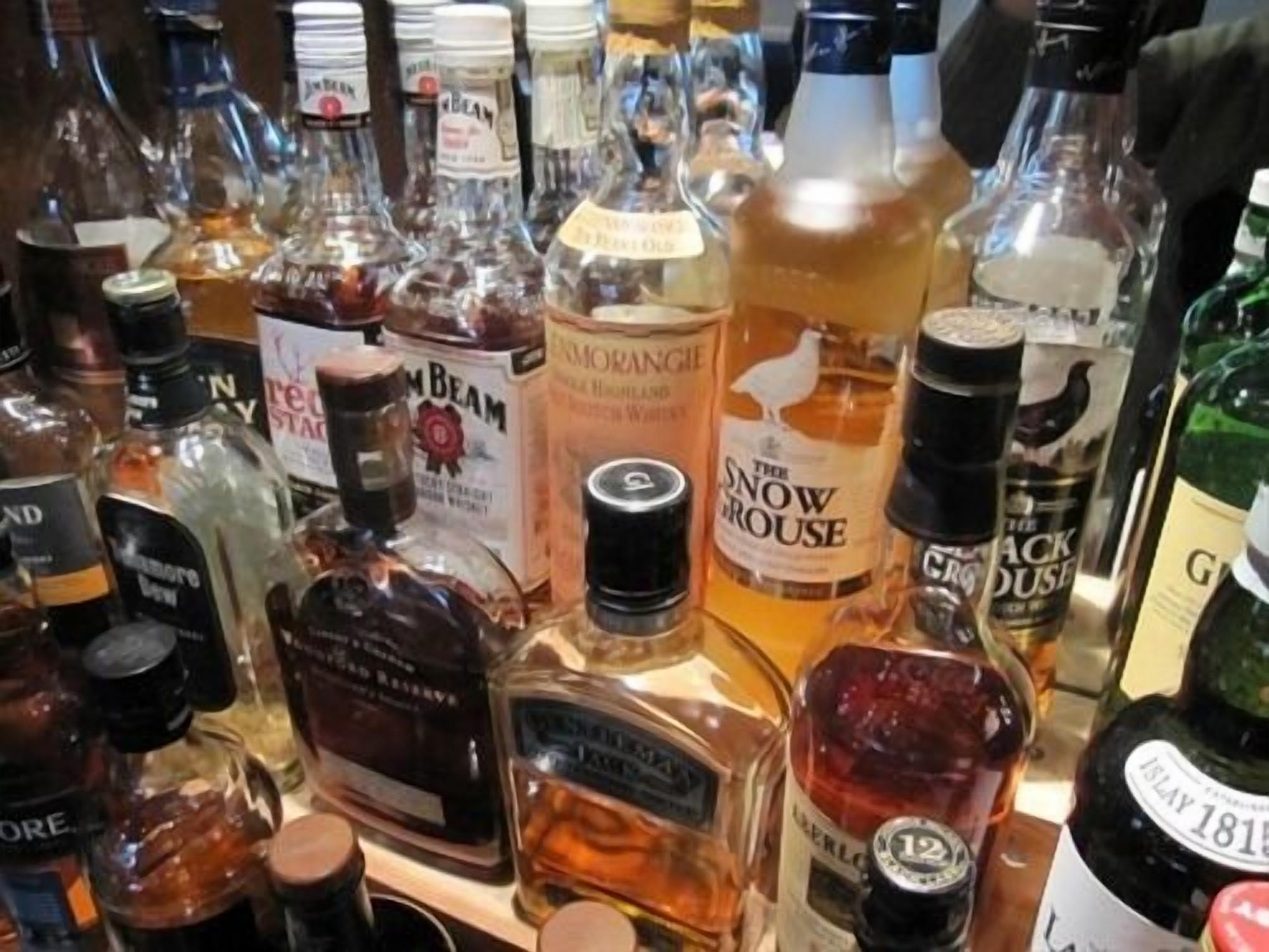 A variety of liquor bottles on a shelf.
