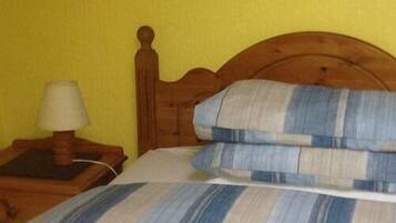 Un letto con testiera in legno, un cuscino a righe e un comodino con una lampada.