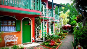 Um edifício colorido com uma porta verde, um banco branco e um caminho vermelho.