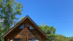 A wooden cabin with a porch, a door, and a small outdoor seating area. - Niseko Cottage Akagera (Kutchan)