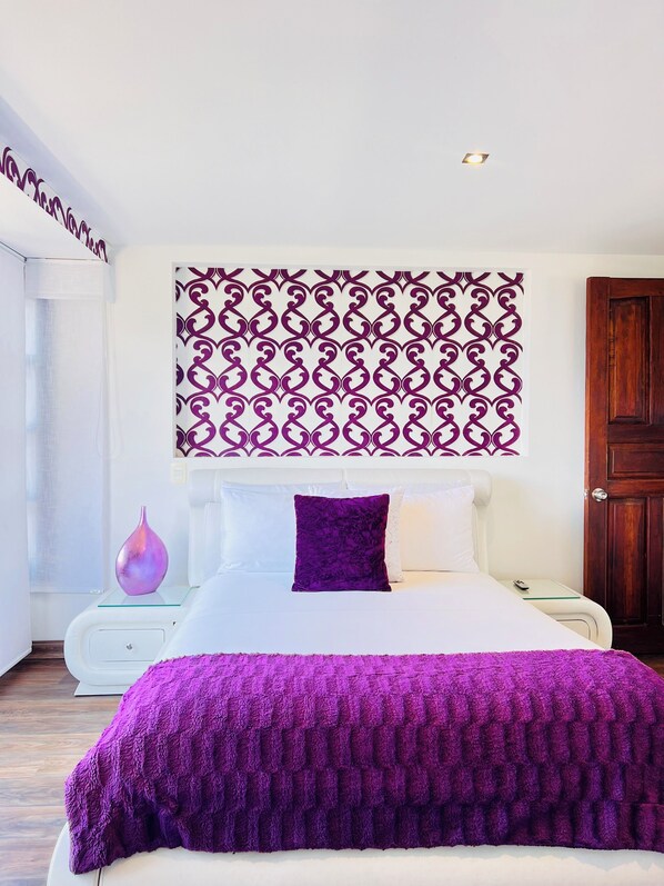 Un dormitorio moderno con una cama grande, un panel decorativo, una mesita de noche y una puerta de madera.